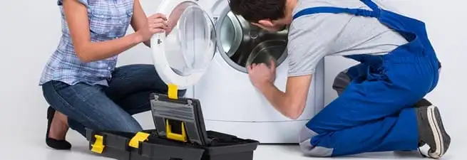 Washer repair technician inspecting a front-load washing machine with tools in Saint Petersburg, FL