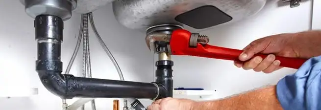 Garbage disposal repair technician tightening the sink drain and disposal connection in Saint Petersburg, FL