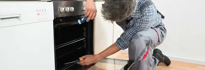 Oven repair technician inspecting and servicing an electric oven in Saint Petersburg, FL
