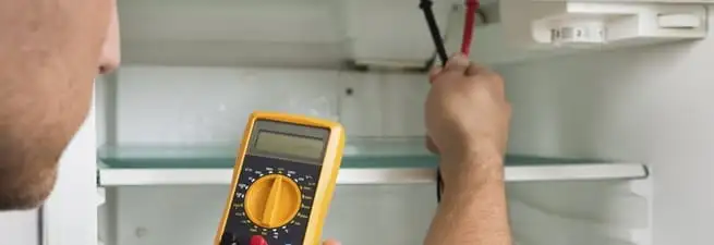 Refrigerator repair technician testing electrical components with a multimeter in Saint Petersburg, FL