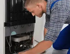 Refrigerator repair technician servicing the compressor and condenser area in Saint Petersburg, FL